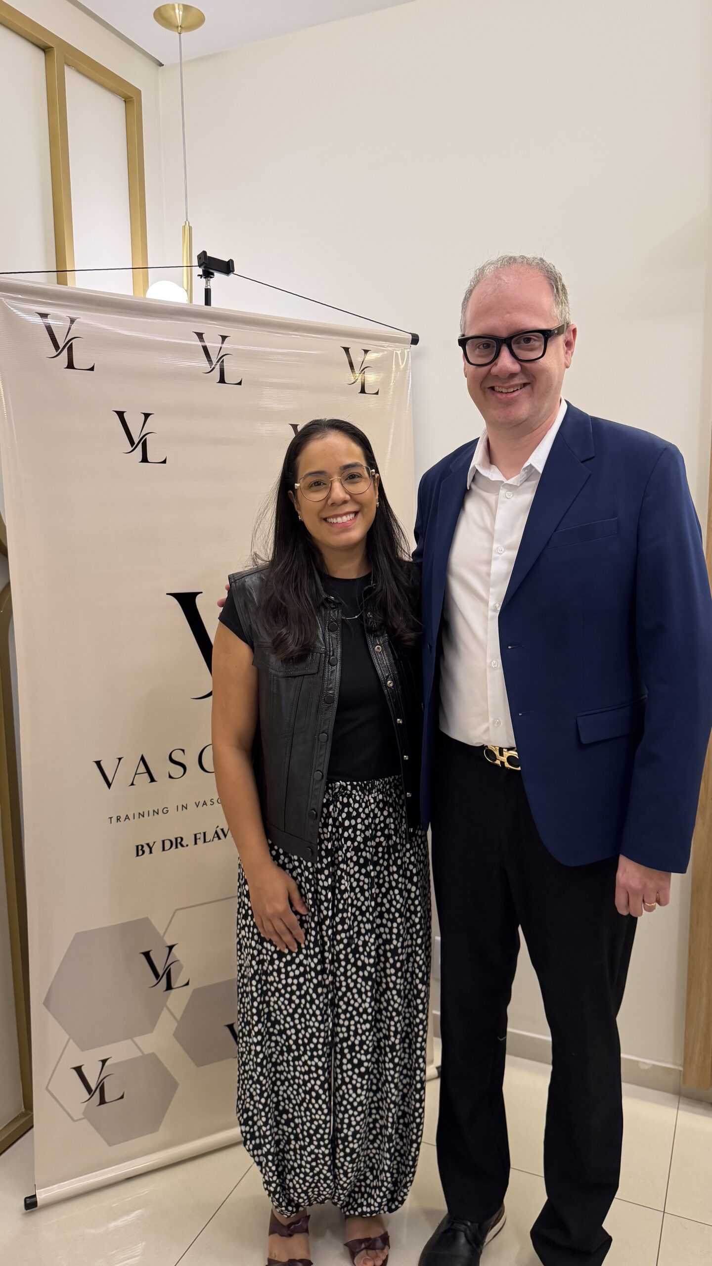 Dr. Flávio Senefonte e a Dra. Daniela diante do banner Vasculipo